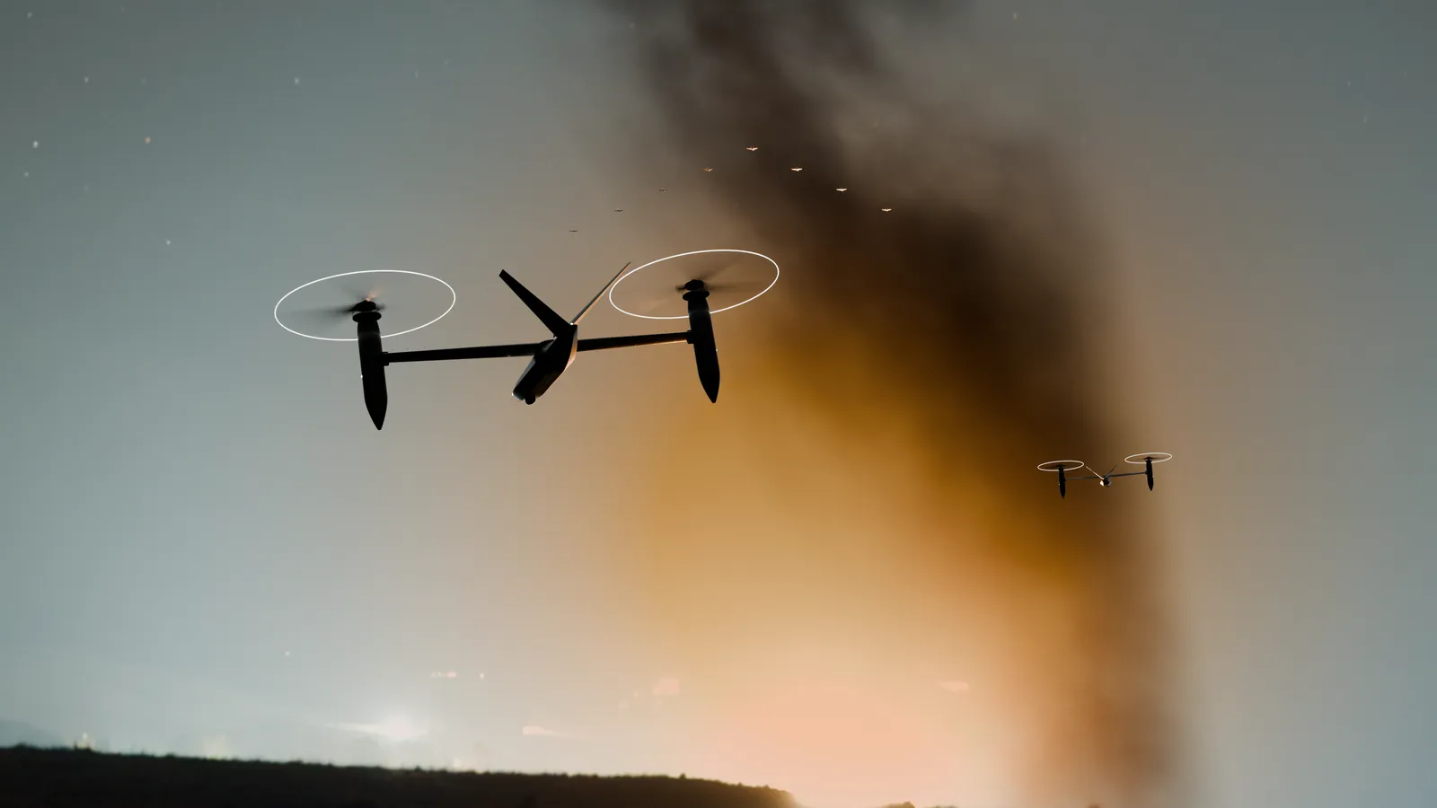Dos drones TORRENTE a contraluz frente a una columna de humo iluminada por un incendio detrás de una loma.